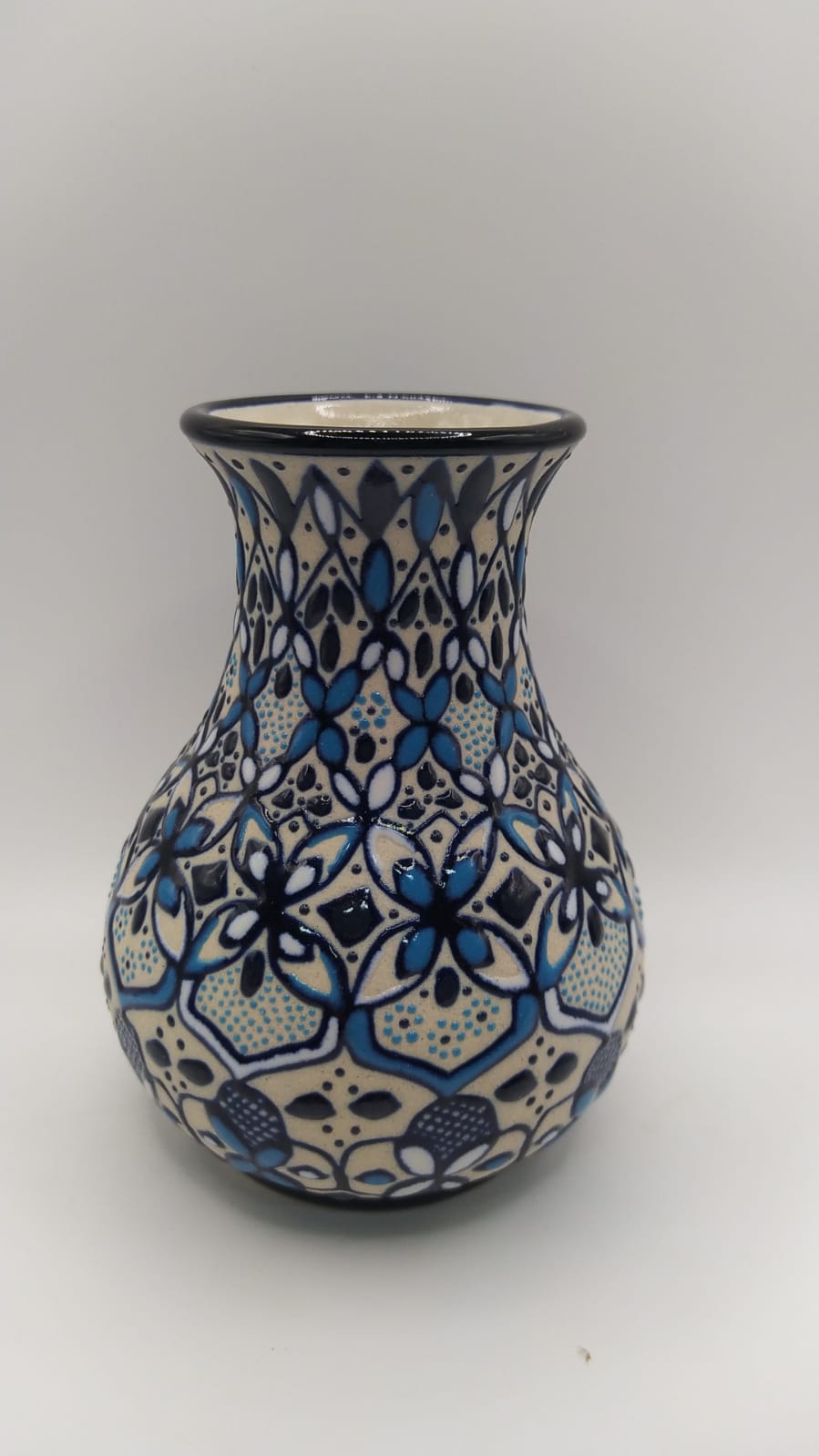 Ceramic vase with blue and black geometric pattern on a white background